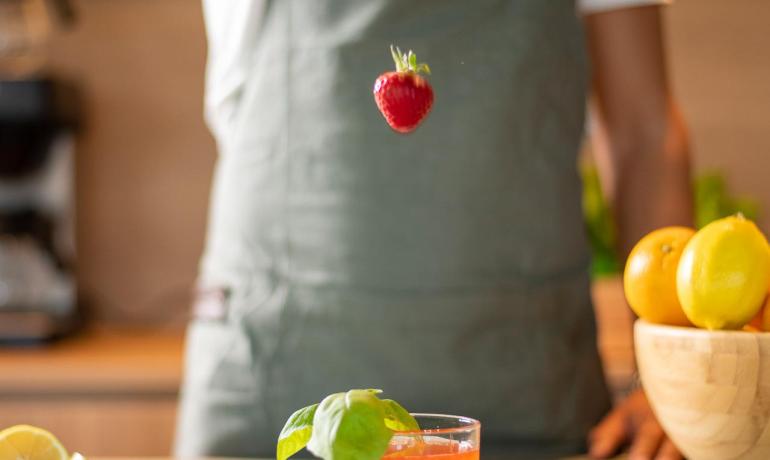 Bartender adding a strawberry to a cocktail in the kitchen.