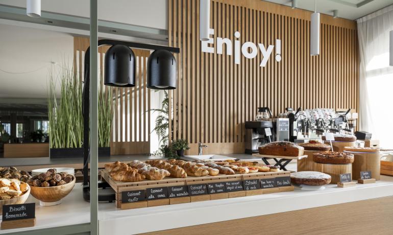 Buffet di dolci con croissant e torte in un ambiente moderno.